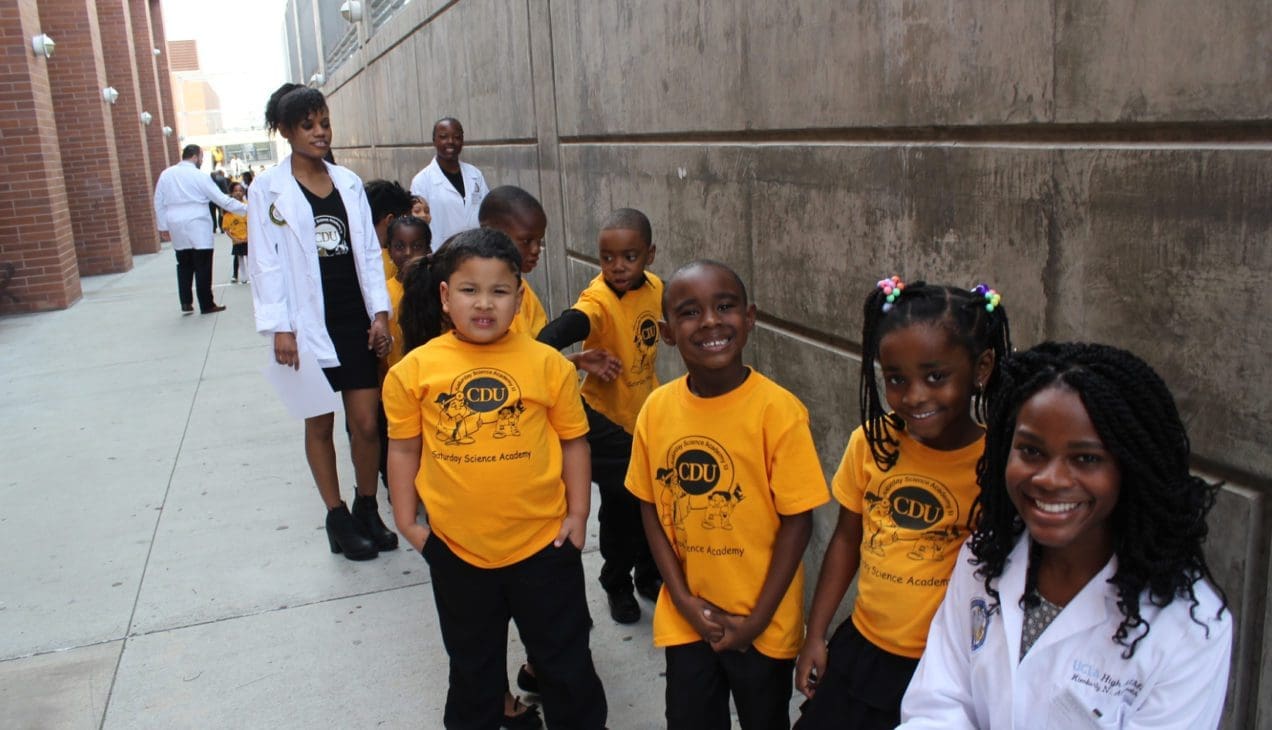 Children in t-shirts smile alongside CDU students